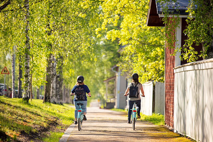 Kaksi lasta pyöräilee kesäisessä puu-Nurmeksessa.