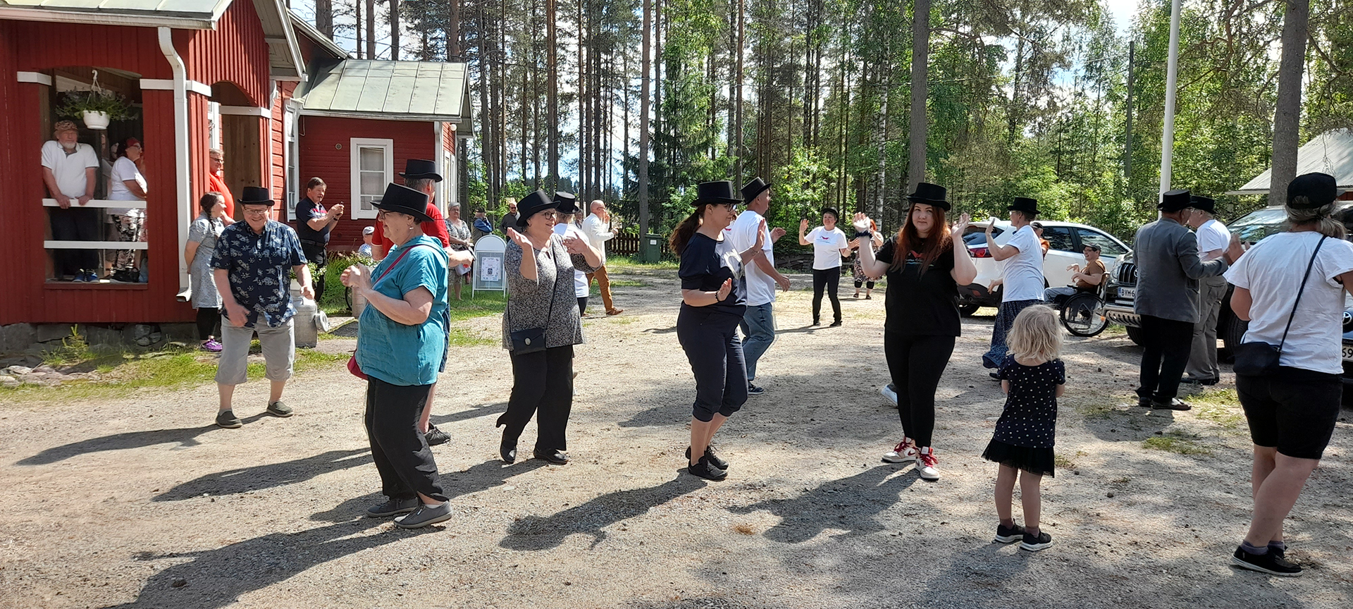 Nurmijärven kyläläiset esittävät kylätanssia kylätalon pihalla.